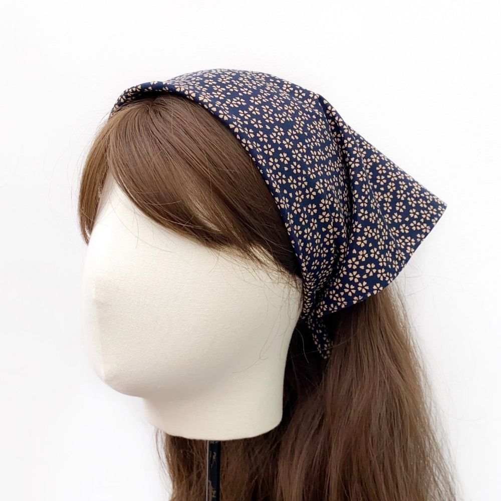 Mannequin head with a navy blue Japanese bandana headscarf with beige sakura cherry blossom patterns