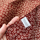 Red Japanese cotton square bandana scarf with cherry blossom floral pattern held by a hand, featuring a 'River Minami' label.