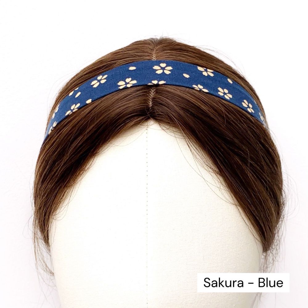 Blue skinny cotton headband with white floral pattern on a mannequin head, labeled 'Sakura - Blue'.