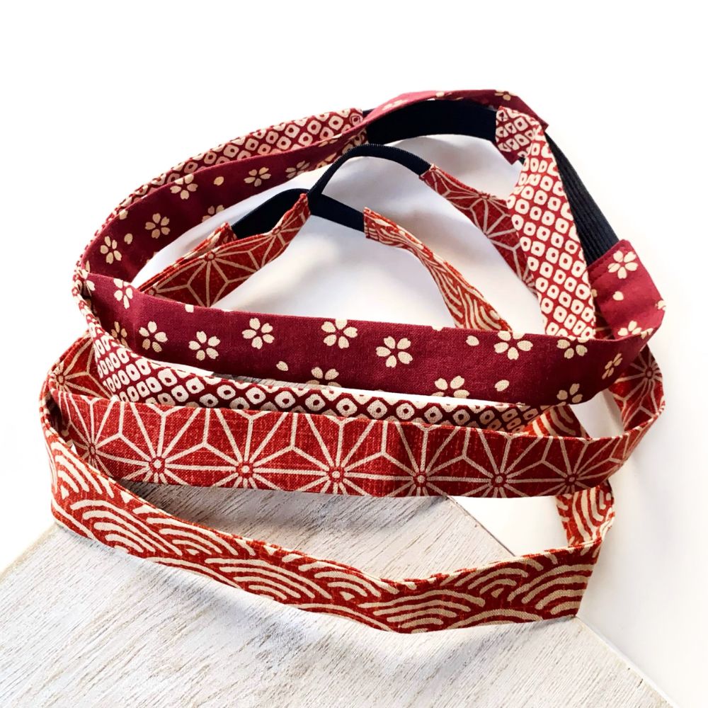 Three Skinny cotton headbands with traditional Japanese patterns in red, burgundy, and cream, arranged on a white surface.