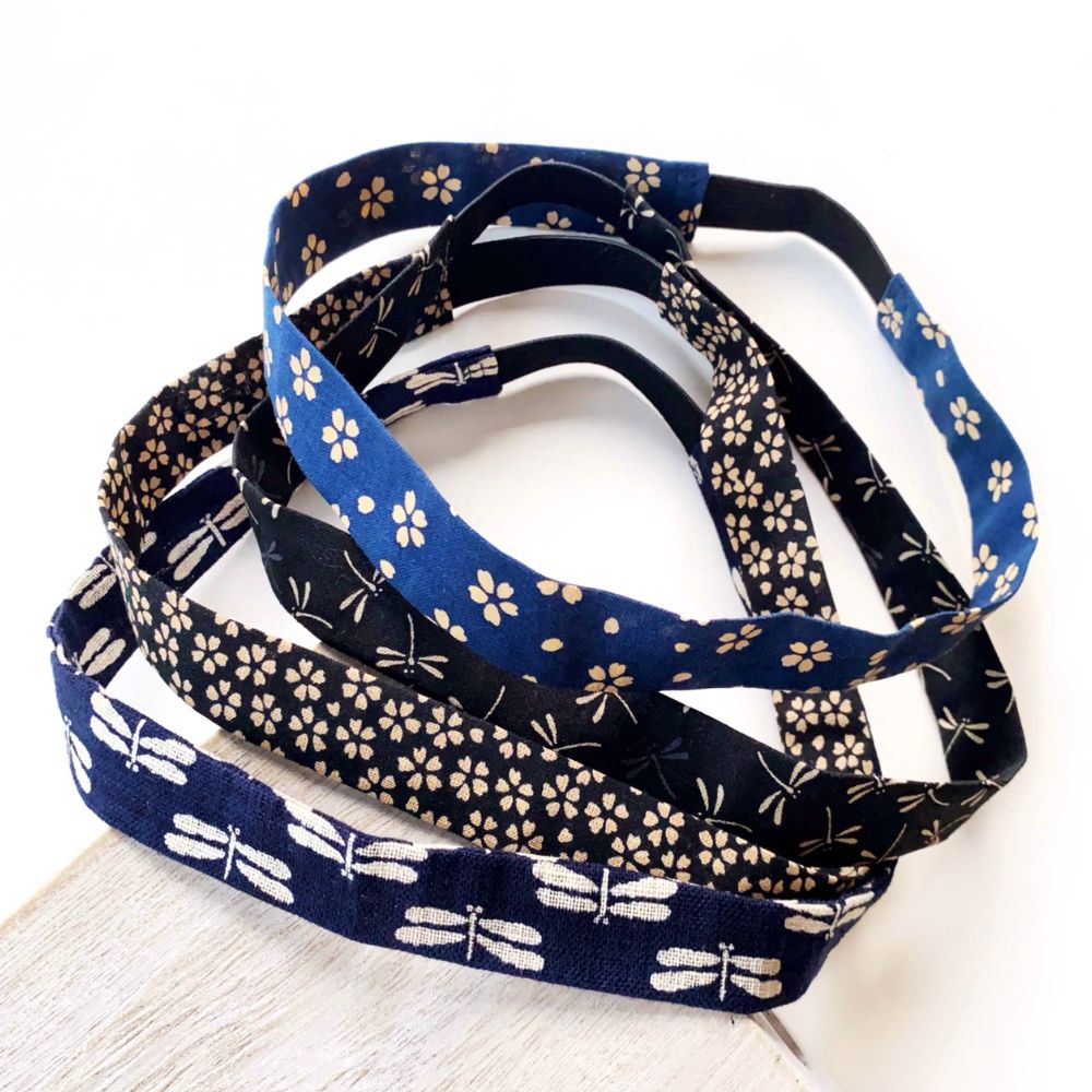 Skinny Japanese cotton headbands with navy blue and black floral patterns, displayed in a stacked arrangement on a light wooden surface against a white background.