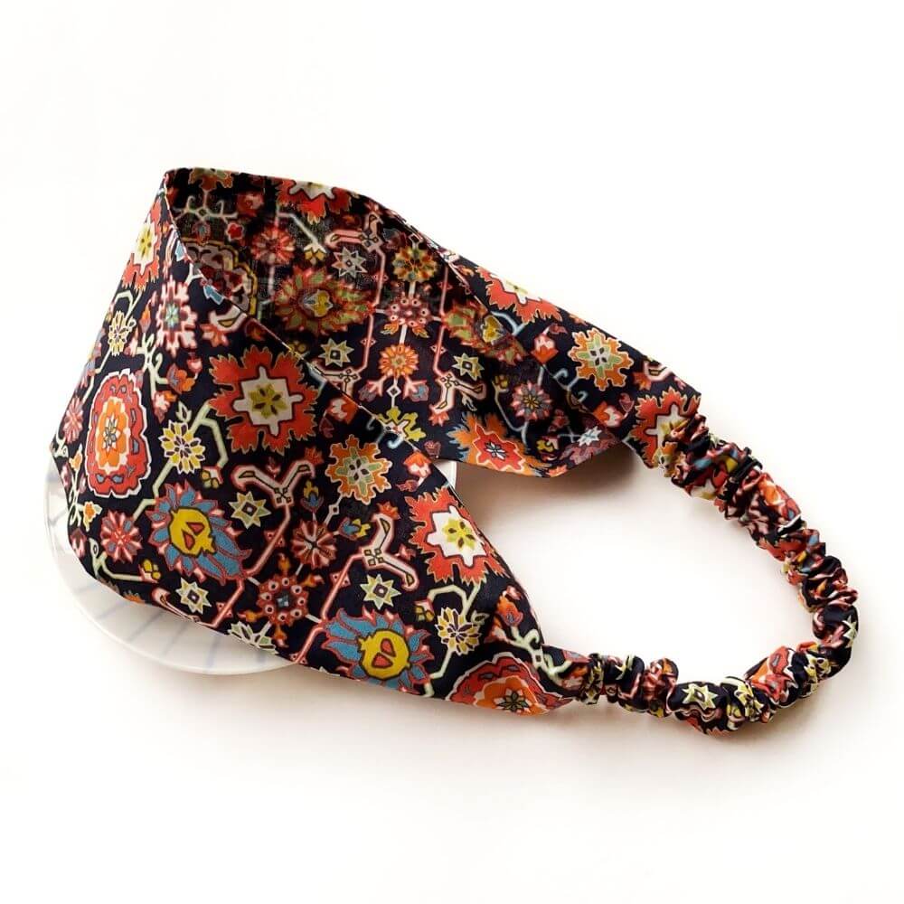 Liberty Cecil print cotton headband with wide flat front and elasticated back, shown in a curved angled view.