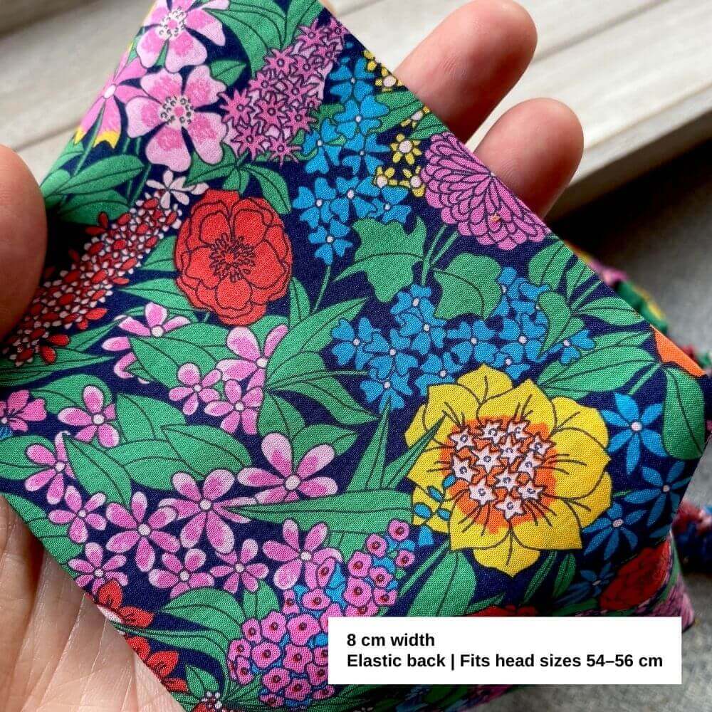 Close-up of Liberty Ciara print cotton fabric, showing vivid red, yellow, pink and blue flowers with green leaves.