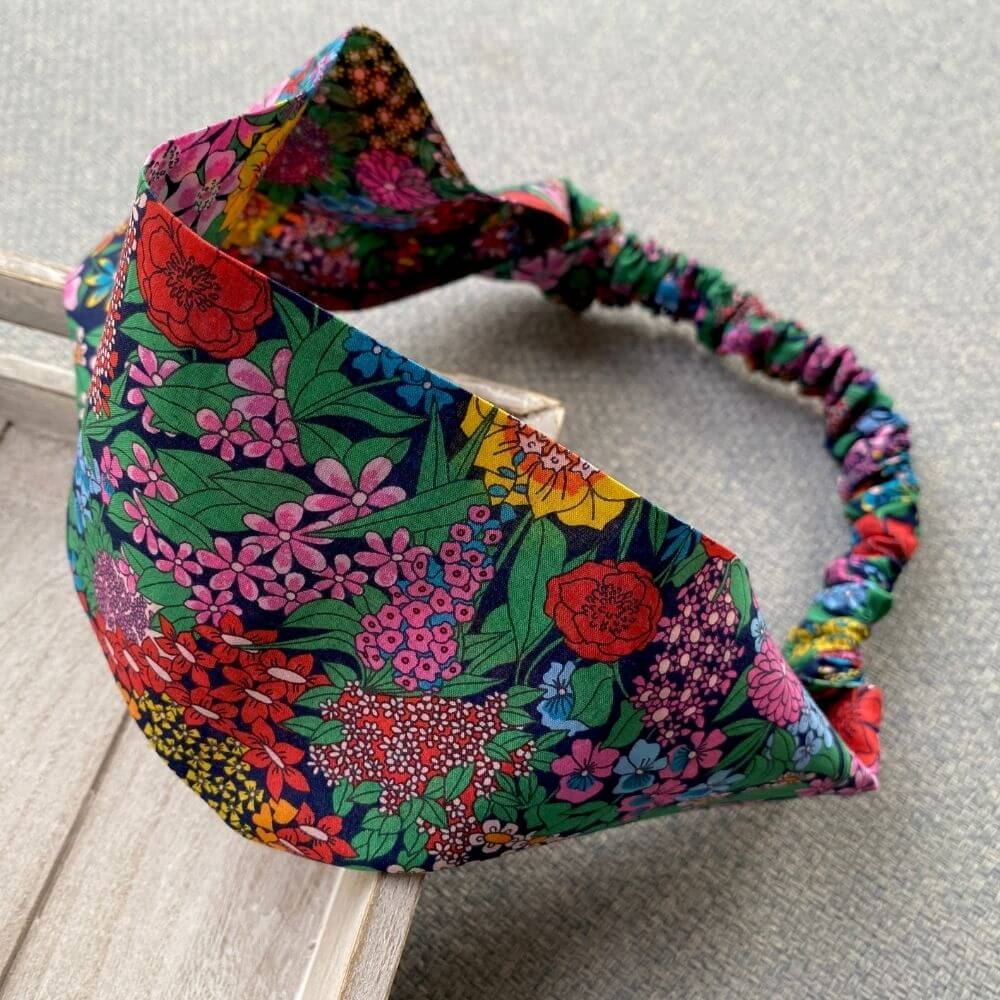 Liberty Ciara cotton headband with flat front and elasticated back, shown angled on a textured surface.