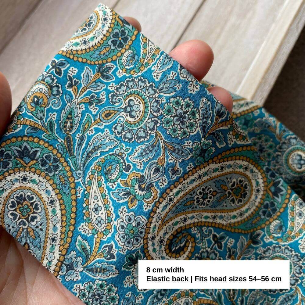 Close-up of the Liberty Lee Manor fabric, showing detailed teal, mustard and cream paisley motifs with an 8 cm wide band label.