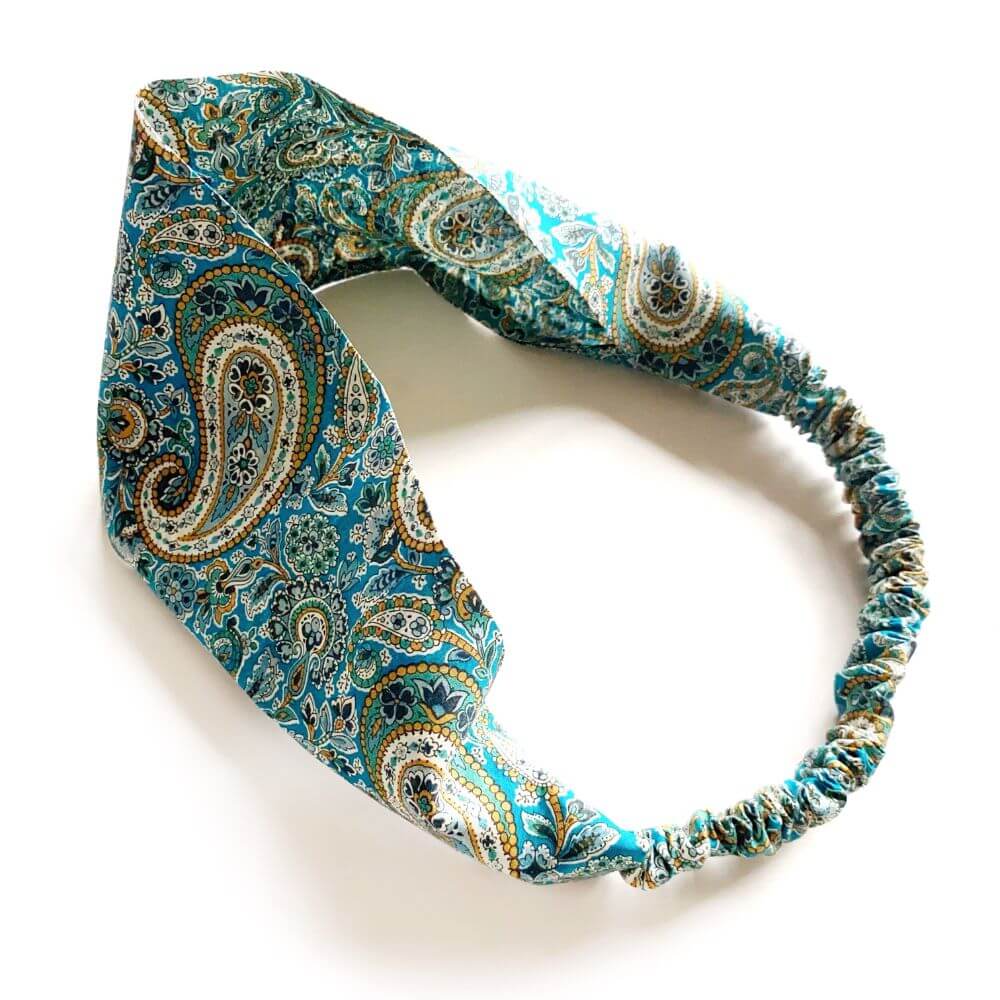 Green paisley patterned headband on a white background