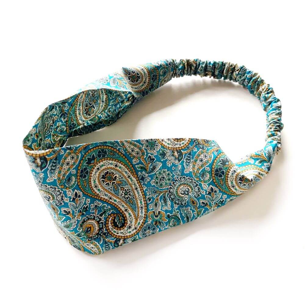 Green and teal paisley patterned headband on a white background