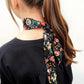 A girl wearing a black floral liberty london silk skinny scarf
