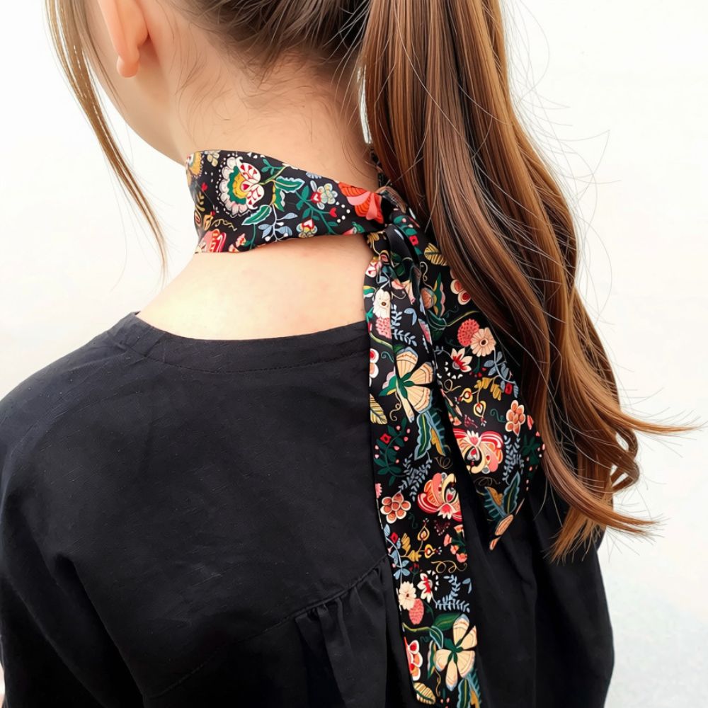 A girl wearing a black floral liberty london silk skinny scarf