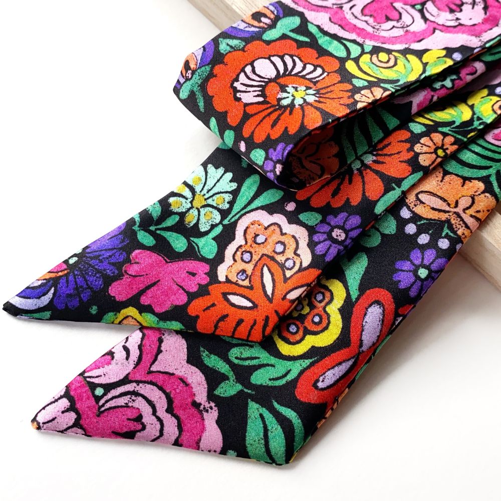 Colorful floral patterned  Liberty silk skinny scarf on a white background