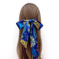 Blue Liberty silk skinny hair scarf tied in a bow on a person's head against a white background