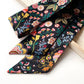 Black floral-patterned Liberty silk twilly skinny scarf on a white background