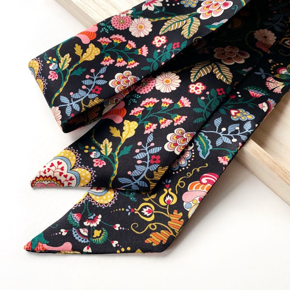 Black floral-patterned Liberty silk twilly skinny scarf on a white background