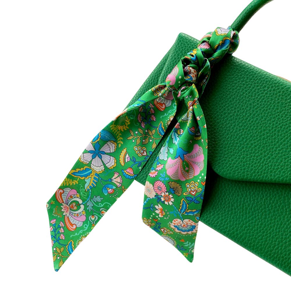 Green handbag with a floral Liberty silk twilly scarf on a white background