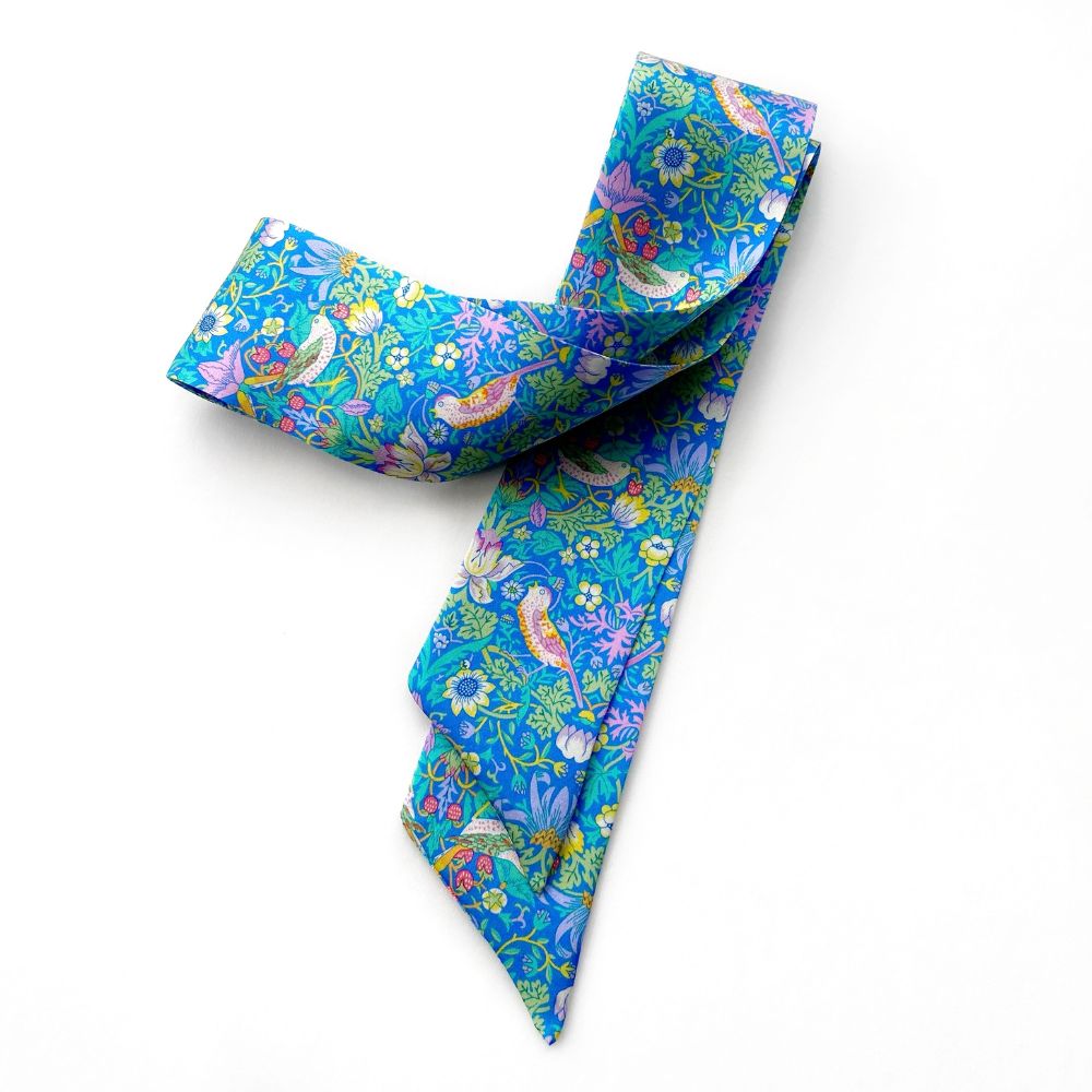 blue strawberry thief patterned liberty silk twilly scarf on a white background