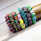 Liberty silk satin skinny scrunchies hair ties in assorted prints stacked on a wooden dowel