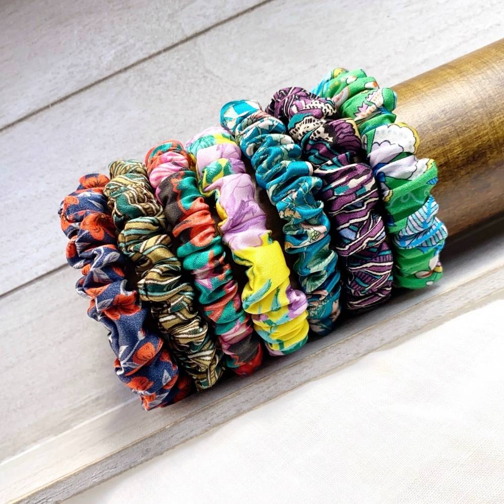 Liberty silk satin skinny scrunchies hair ties in assorted prints stacked on a wooden dowel