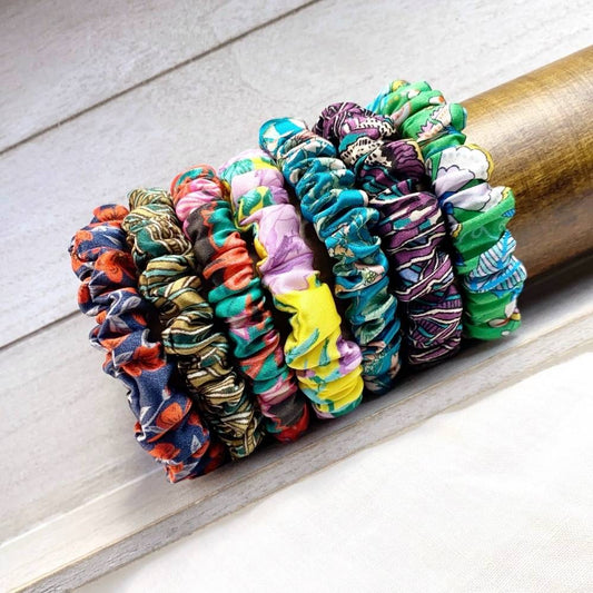 Liberty silk satin skinny scrunchies hair ties in assorted prints stacked on a wooden dowel