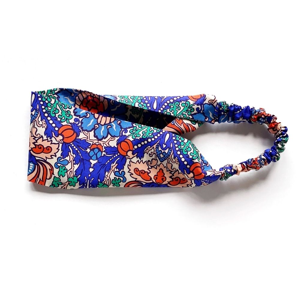 Liberty London Tana Lawn cotton headband with a vibrant multicolor floral and paisley print, featuring a gathered elastic back, photographed on a clean white background.