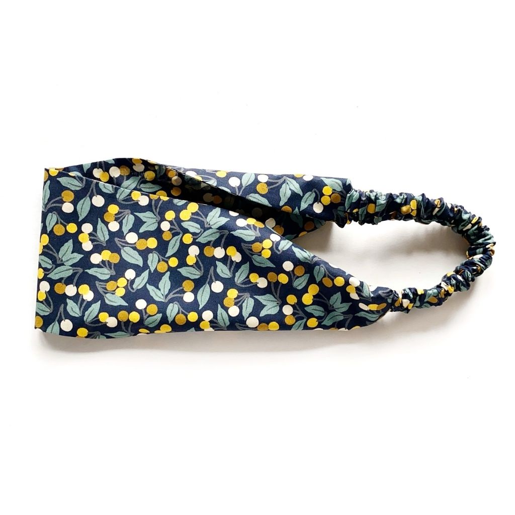 A Liberty London Tana Lawn cotton headband with a navy blue background and a yellow, white, and green citrus fruit pattern, featuring a gathered elastic back, shown on a white background.