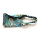 A Liberty London print lee manor Tana Lawn cotton  headband with a teal and blue paisley pattern and an elastic back, shown on a plain white background.