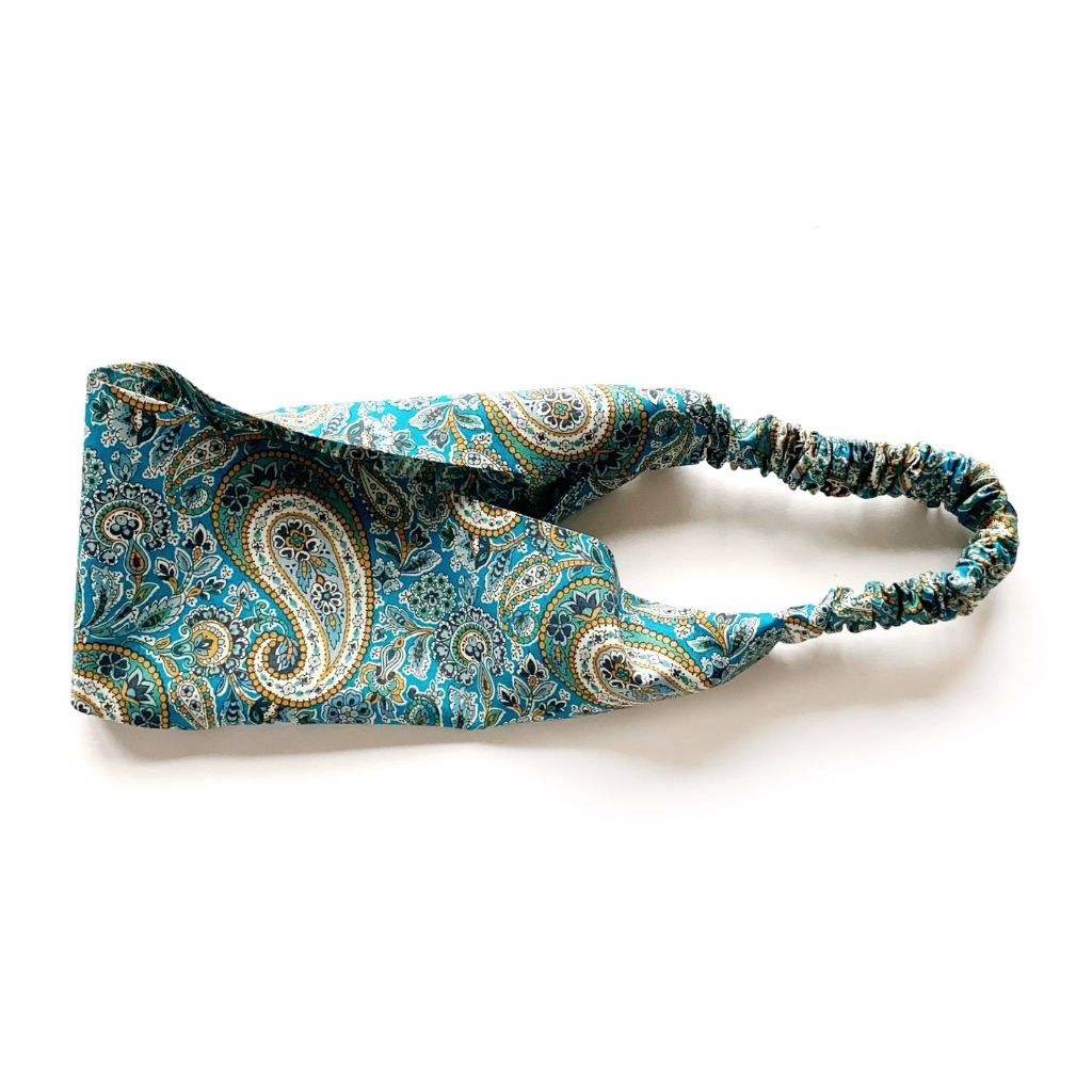A Liberty London print lee manor Tana Lawn cotton  headband with a teal and blue paisley pattern and an elastic back, shown on a plain white background.