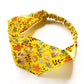A yellow Liberty London Tana Lawn cotton  headband with a colorful floral print, featuring an elastic band, shown on a white background.