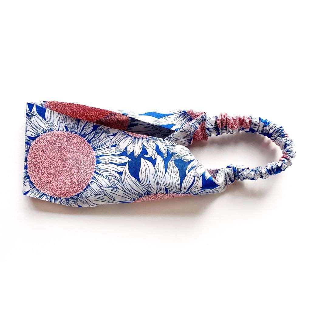 Liberty London Tana Lawn cotton headband featuring a blue and white sunflower print and a matching elastic back, shown on a plain white background.