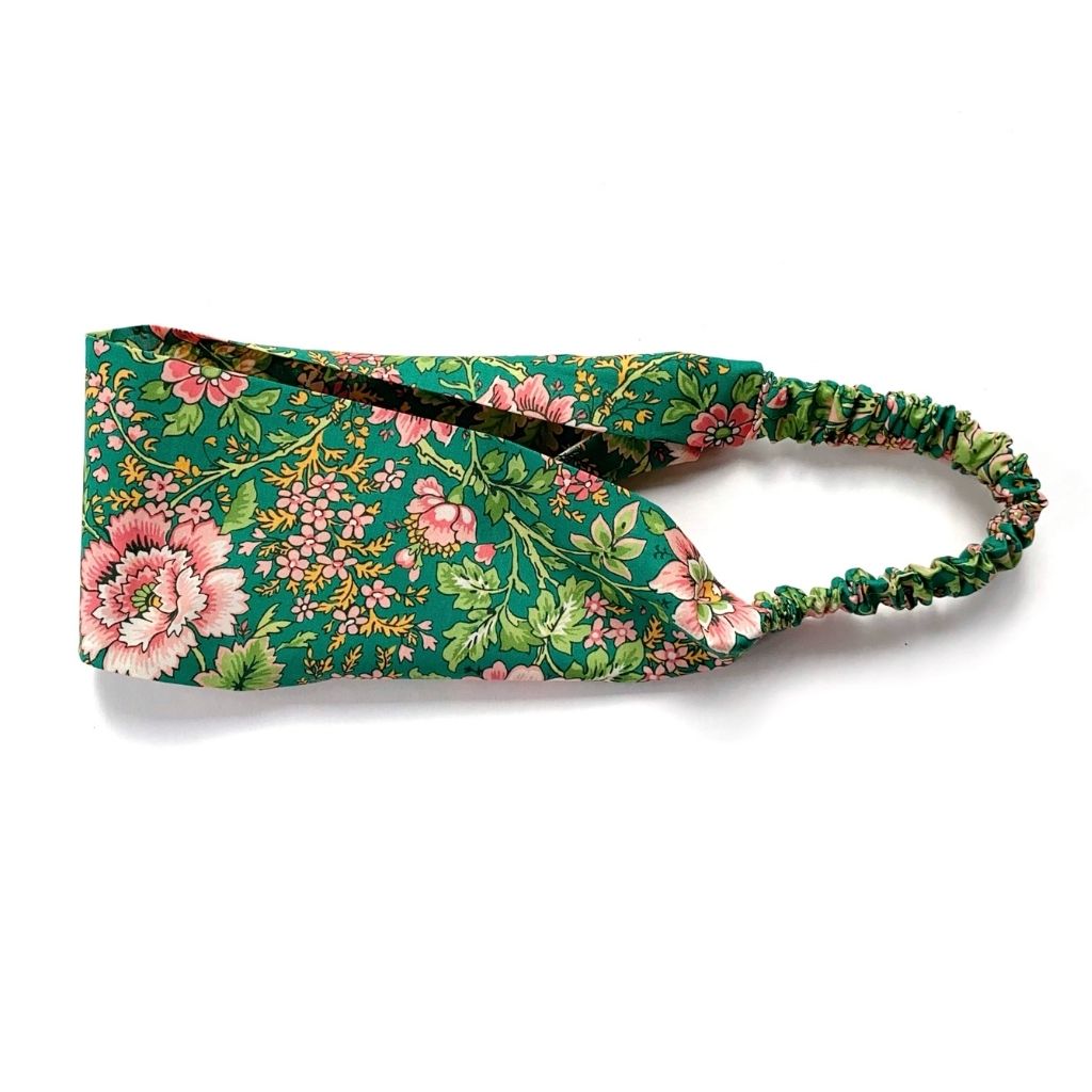 Liberty London Tana Lawn cotton headband with a green floral print and an elastic back, shown on a plain white background.