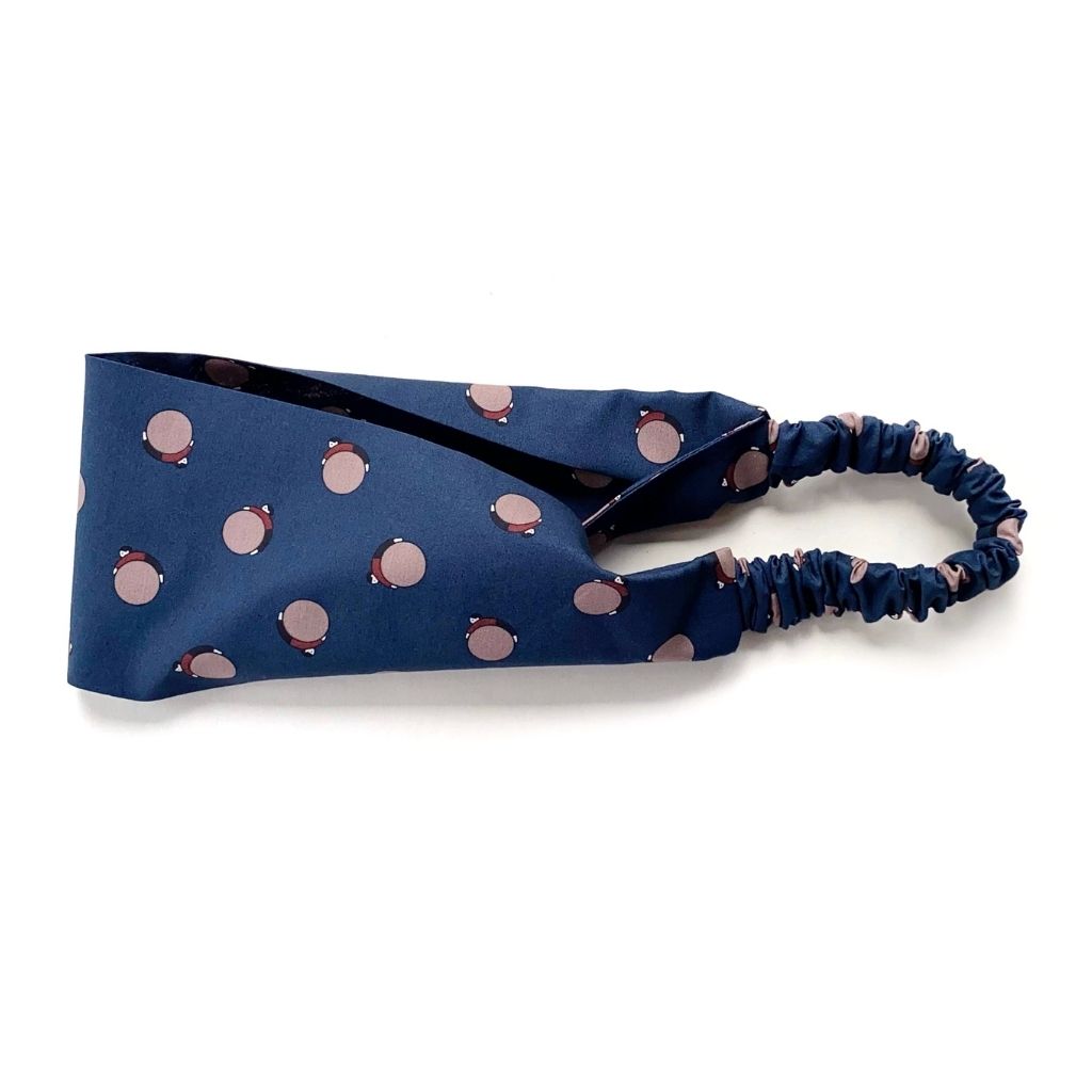 A navy blue Liberty London Tana Lawn cotton  headband, featuring an elasticized back strap, shown on a plain white background.