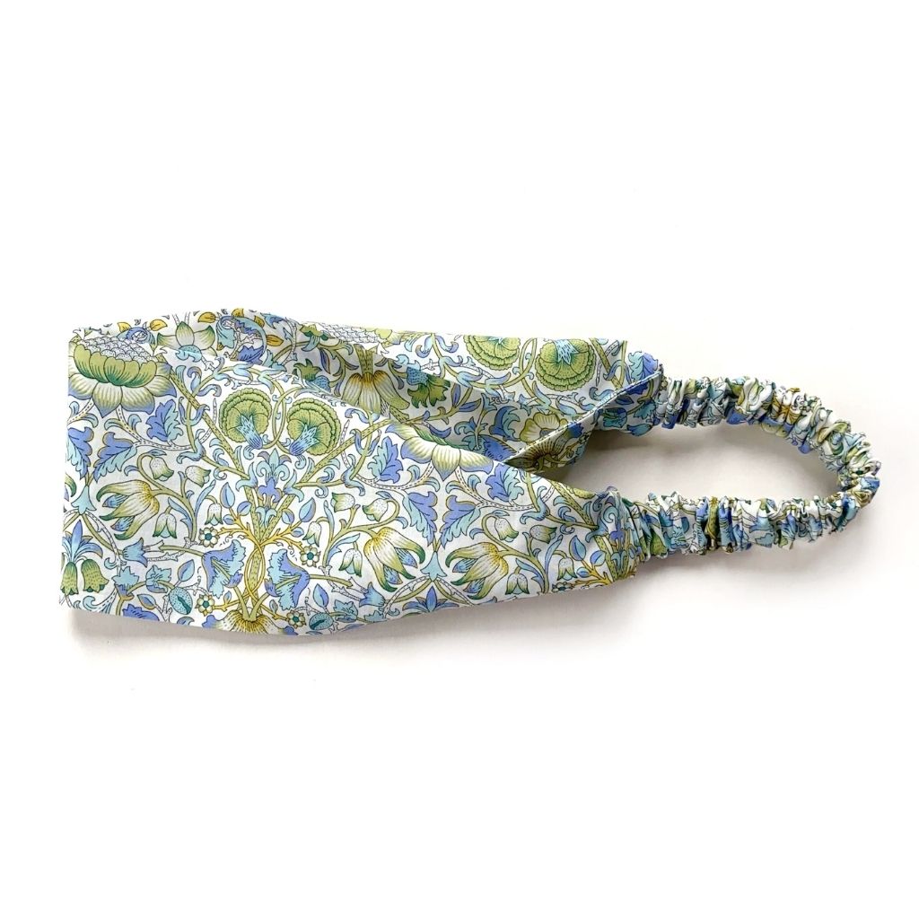 A Liberty London Tana Lawn cotton headband in william morris print" lodden" with a green, blue, and white floral pattern, featuring an elastic band, shown on a plain white background.