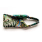 A Liberty London Tana Lawn cotton headband with a vibrant tropical leaf print in shades of green, blue, yellow, and orange, featuring a matching elasticated back, shown on a plain white background.