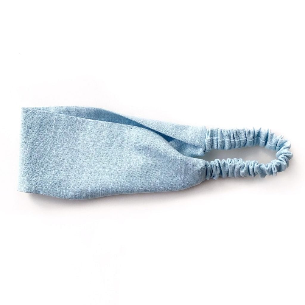A light blue flat linen headband with an elastic back, displayed on a clean white background.