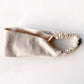 A light cream linen headband with an elastic back, displayed on a clean white background.