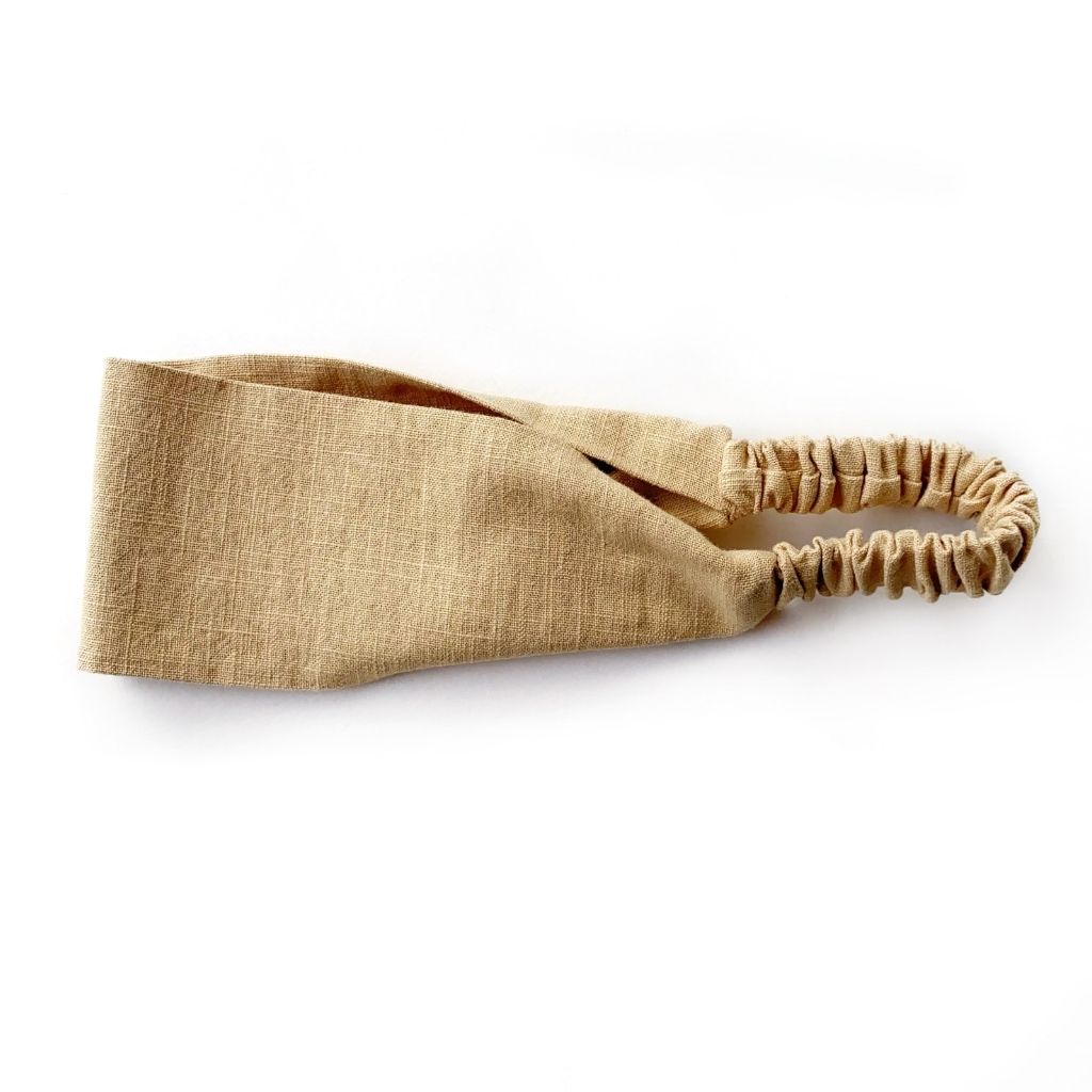 A sand linen headband with an elastic back, displayed on a clean white background.