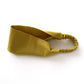 A mustard yellow flat linen headband with an elastic back, displayed on a clean white background.