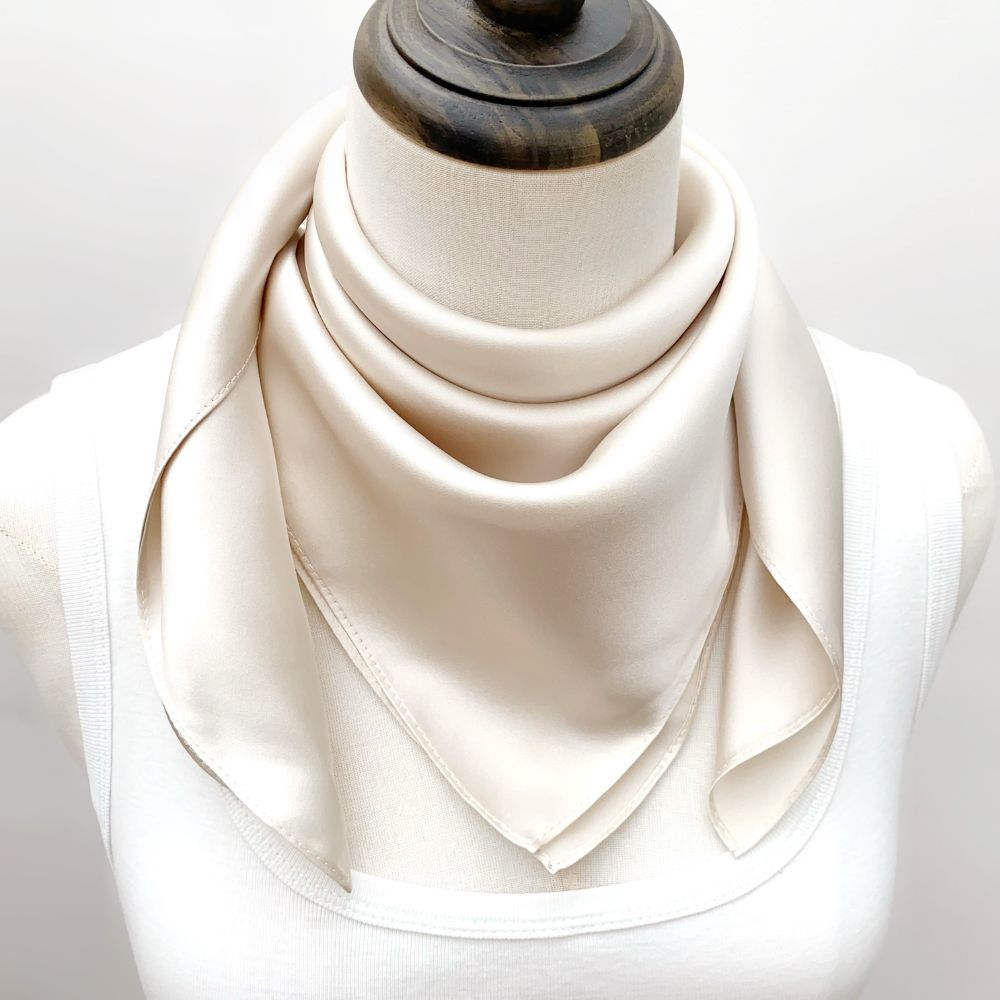 mannequin wears a solid light beige mulberry silk square bandana scarf around her neck