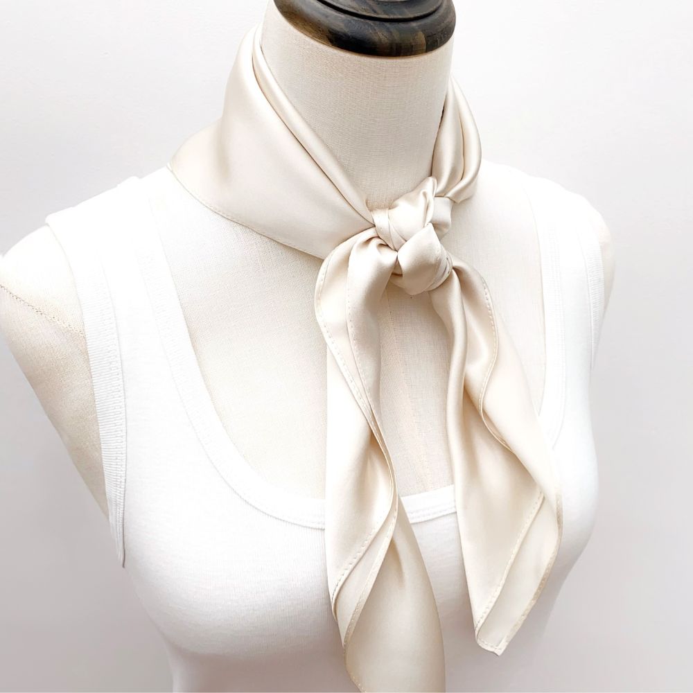 mannequin wears a solid light beige mulberry silk square bandana scarf around her neck