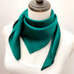 mannequin wears a solid emerald green mulberry silk square bandana scarf around her neck