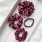 Set of maroon silk satin scrunchies on a light wooden surface