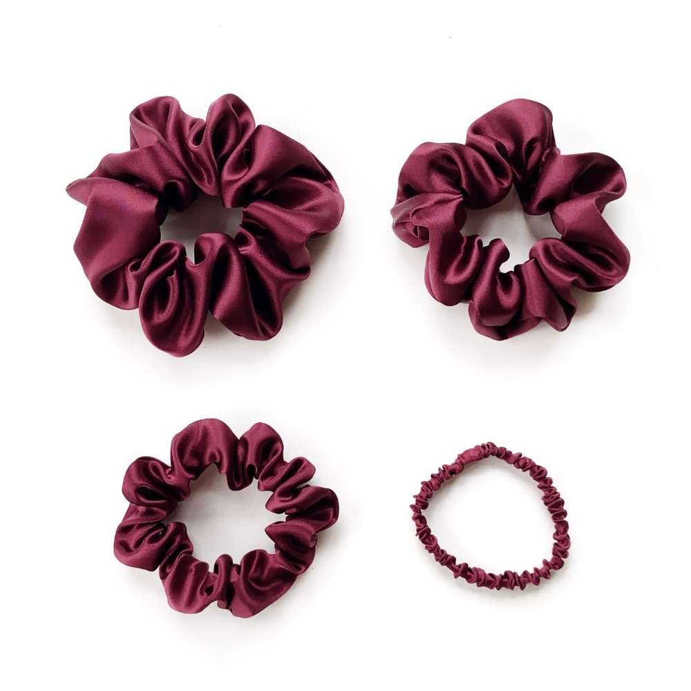 Four burgundy silk satin hair scrunchies on a white background