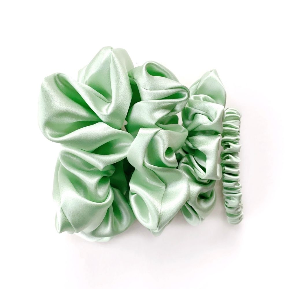 Set of mint green mulberry silk scrunchies and hair ties on a white background
