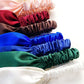 Stack of colorful mulberry silk headbands in various colors on a white background