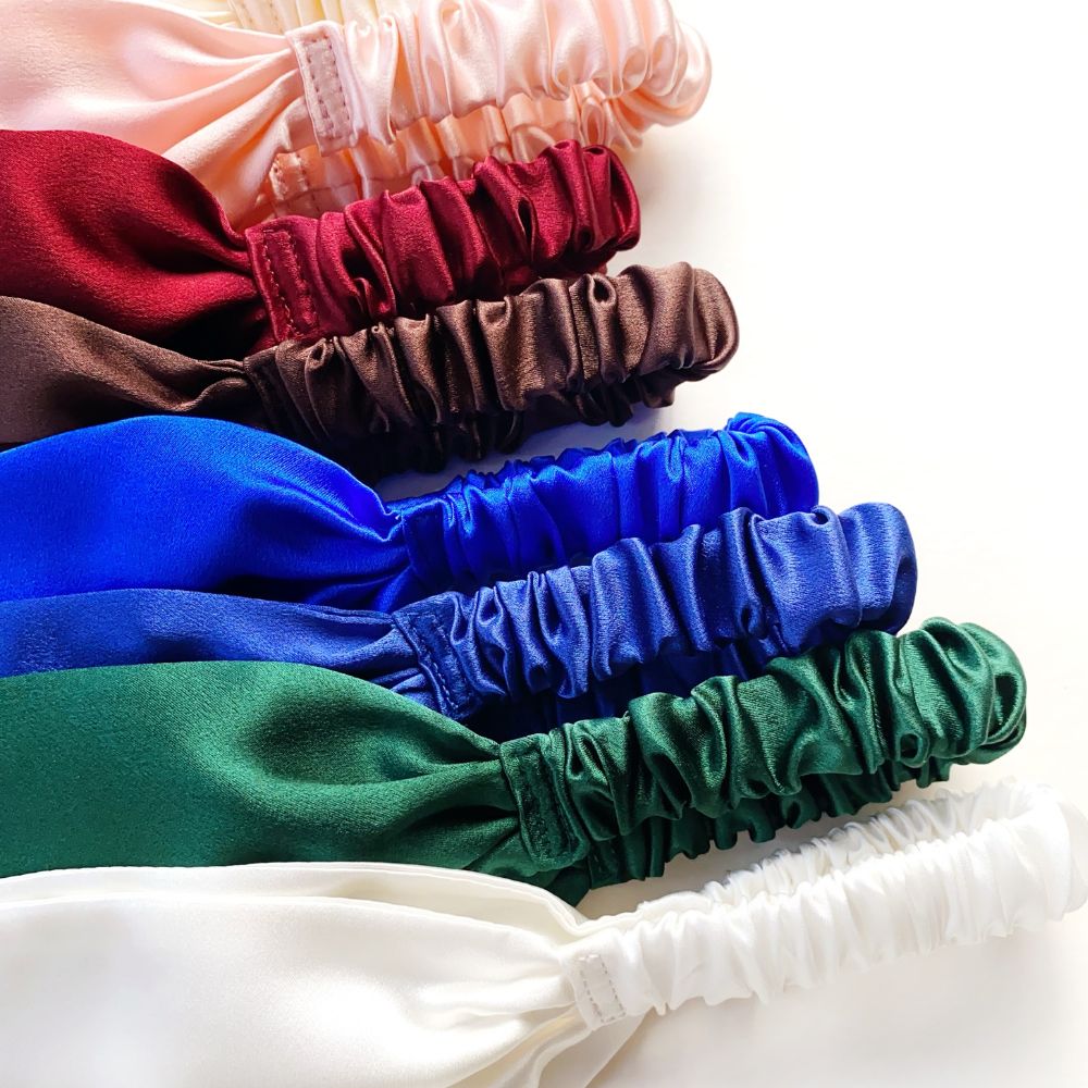 Stack of colorful mulberry silk headbands in various colors on a white background
