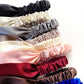 Stack of colorful mulberry silk satin headbands on a white background