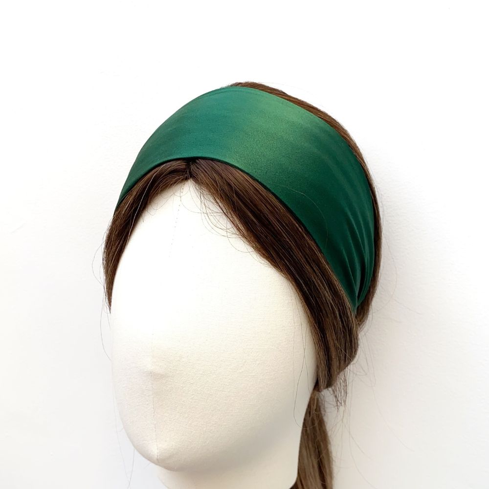 Green silk headband worn on a mannequin head against a white background
