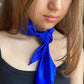 Royal blue Mulberry silk satin scarf tied in a loose front knot on a woman wearing a black top