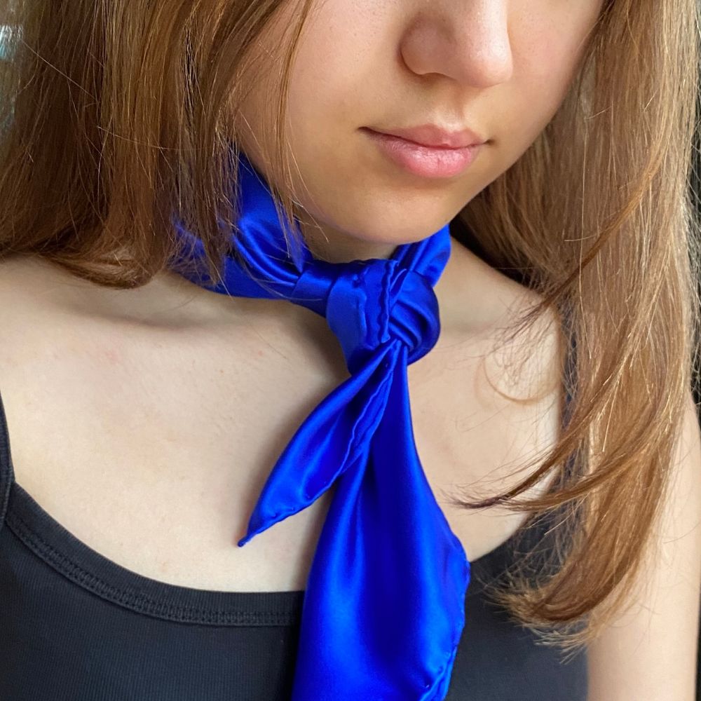 Royal blue Mulberry silk satin scarf tied in a loose front knot on a woman wearing a black top