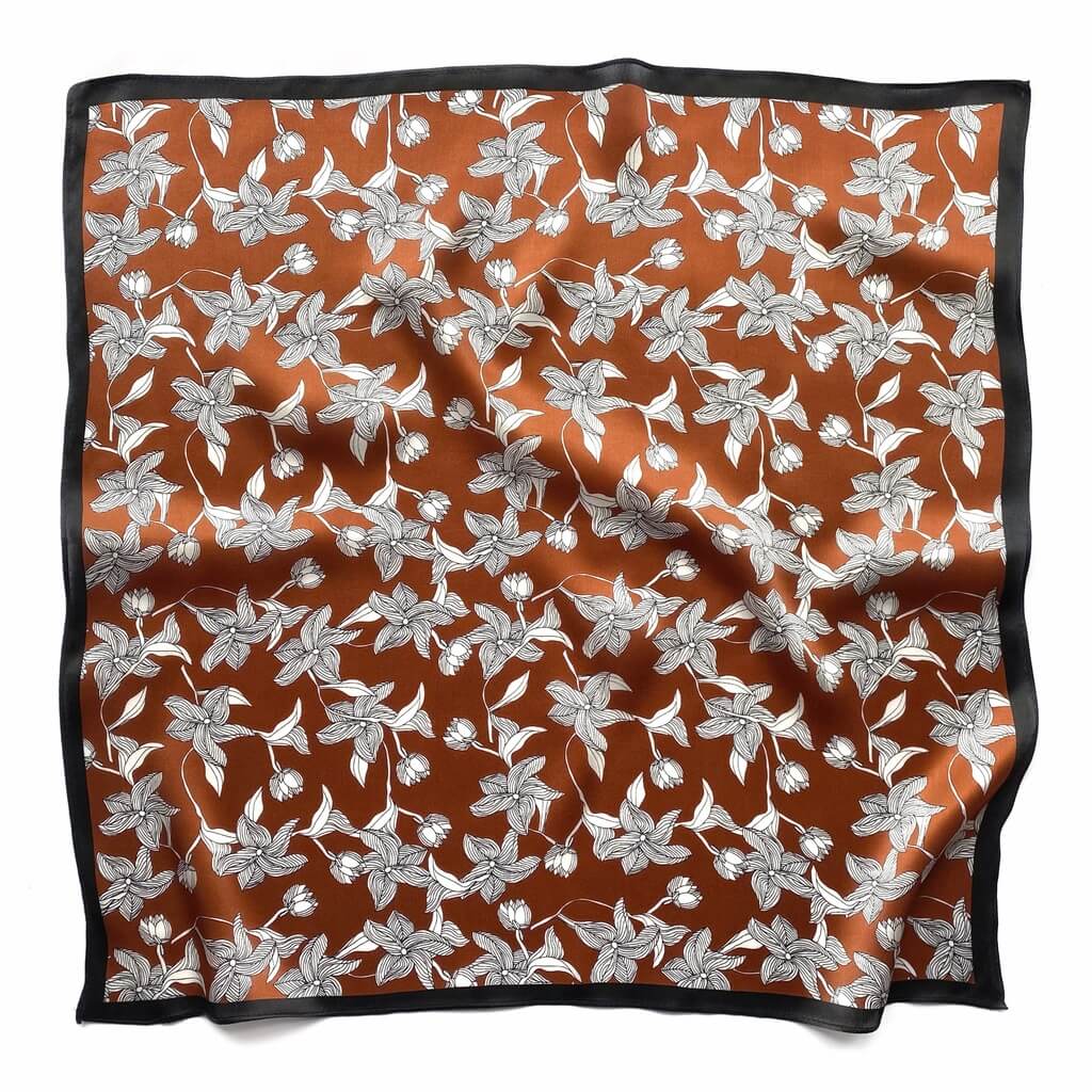 Mulberry silk square scarf with a black and white line art floral pattern on a brown background, framed with a black border and laid flat on a white background.
