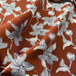 Close-up detail of a mulberry silk scarf featuring a white sketched floral pattern on a warm brown background.